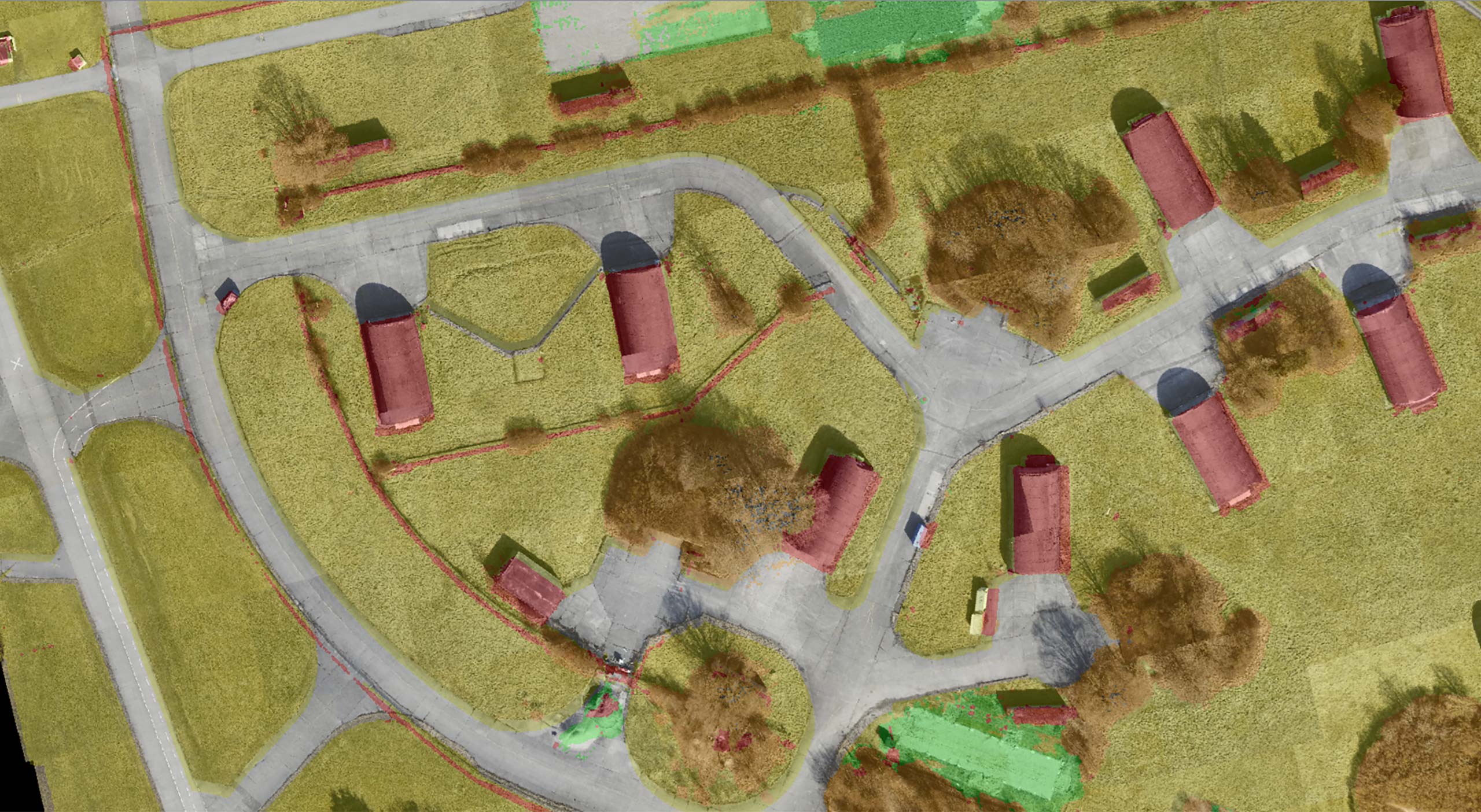 The image shows color coded AI-generated land cover data. Red areas are non-traversable. Green and orange areas are grass and fields. Grey areas are paved areas.
